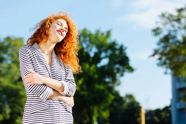 Güneşli bir günün tadını çıkaran rahat kıvırcık saçlı kadın