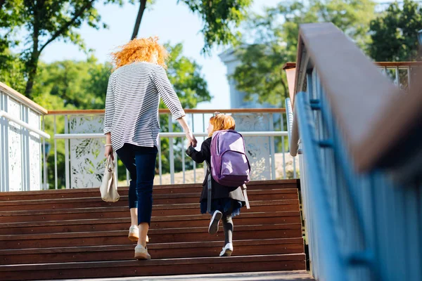 Задоволена маленька дівчинка ходить з мамою перед уроками — стокове фото