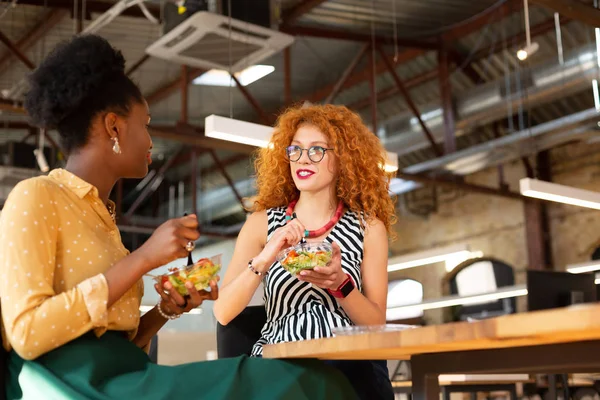 Mulher ruiva comendo e conversando com colega — Fotografia de Stock