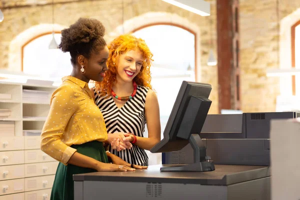 Businesswoman teaching employee to use cashier system