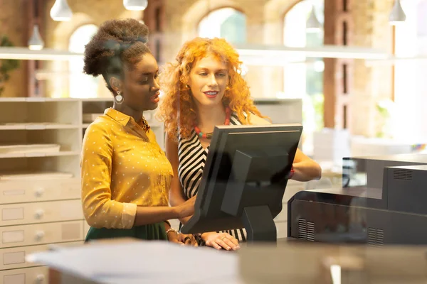 Koyu tenli genç kasiyer patrona sorular soruyor