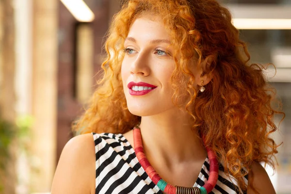 Young woman wearing necklace looking into window — Stock Photo, Image