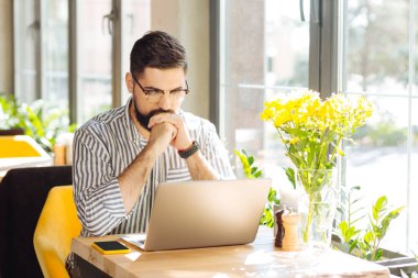 İşle meşgul. Onun laptop yazarken güzel iyi görünümlü adam gülümseyen