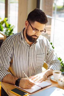 İyi görünümlü ciddi adam not defterine yazma