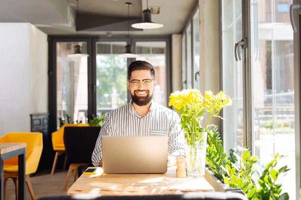 Happy bebaarde man zit aan de tafel — Stockfoto