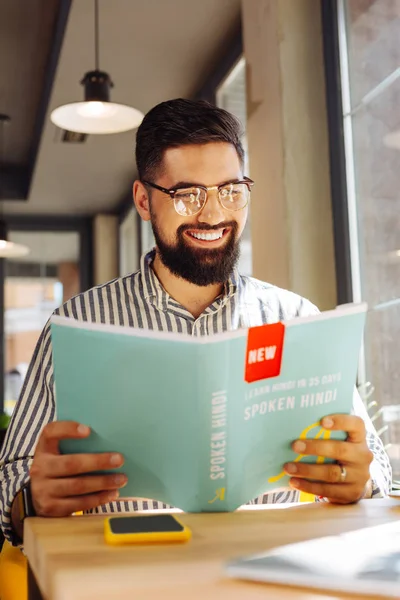 Positive bearded man studying a new language by himself