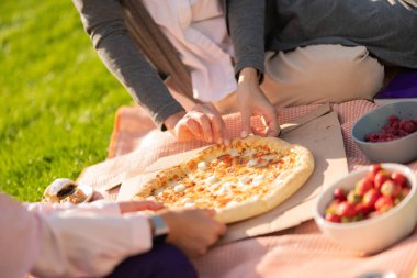 Öğle yemeği yerken pizza ve meyve yiyen iki öğrenci