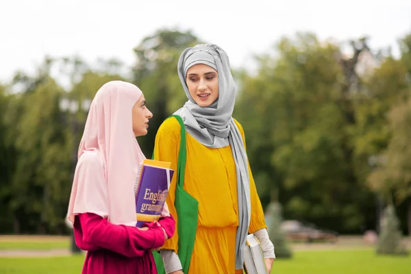 Muslim student wearing yellow dress talking to friend