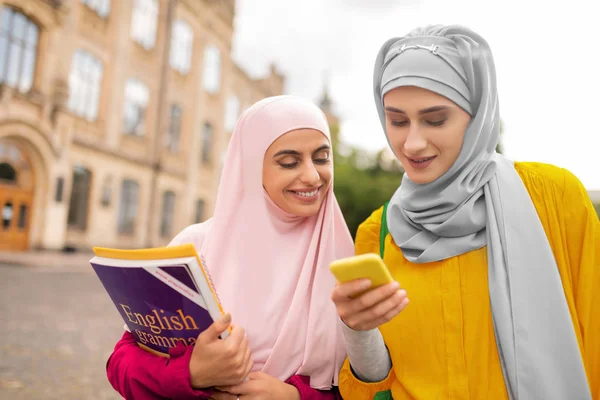 オンライン地図を使用しながらスマートフォンを使用して2人のイスラム教徒の女性 — ストック写真