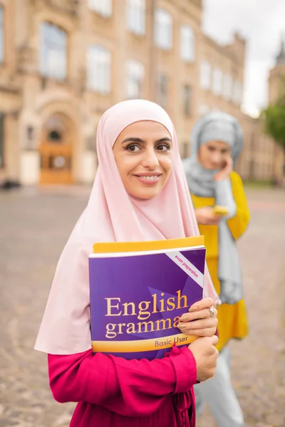 英語の本を持つ暗い目のイスラム教徒の女性を照らす — ストック写真