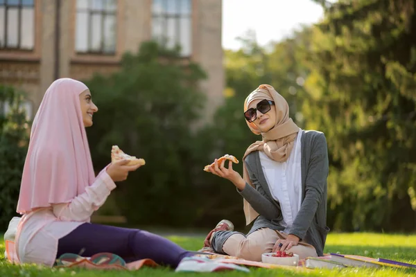 外の友人とピザを食べるサングラスのイスラム教徒の女性 — ストック写真