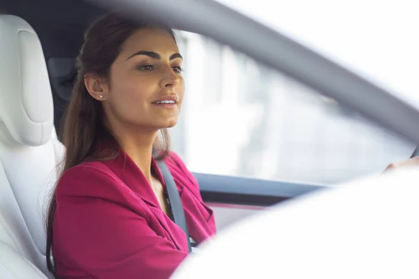 Beautiful businesswoman looking into back mirror in the car
