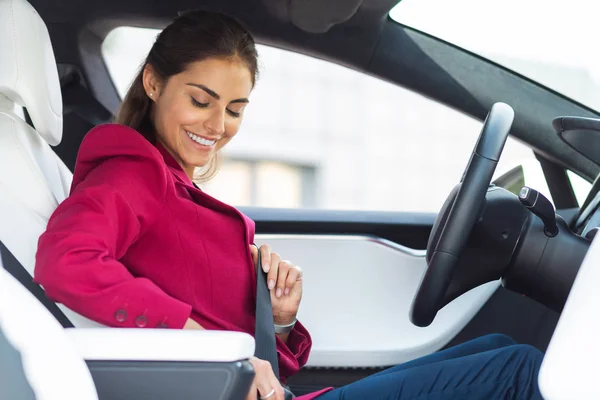 Sorrindo mulher fixando cinto de segurança enquanto sentado em seu carro — Fotografia de Stock