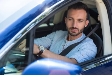 Sakallı adam arabasını sürerken kendini iyi hissediyor.