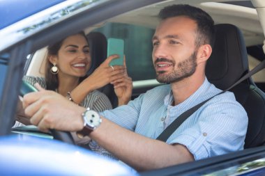 Koca araba sürerken fotoğraf yaparken gülen karısı