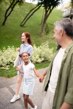 Güzel evlatedinilmiş kız anne ile yürürken baba ile konuşurken