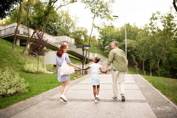 Pais andando com a menina adotada de mãos dadas — Fotografia de Stock