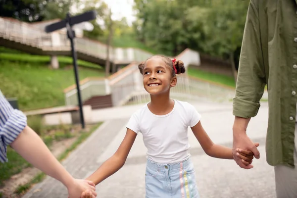 Fille faire drôle visage tout en marchant avec les parents — Photo