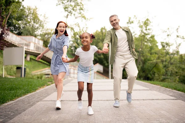 Figlia afro-americana che corre mentre cammina con i genitori — Foto Stock