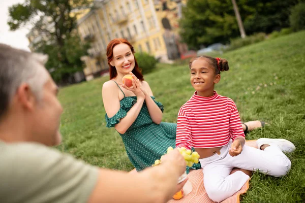 Meisje glimlachend terwijl het nemen van druiven en het hebben van familie picknick — Stockfoto