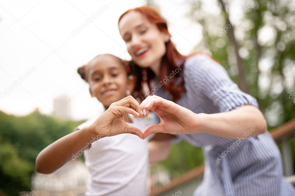 Daughter and mother making heart with their hands