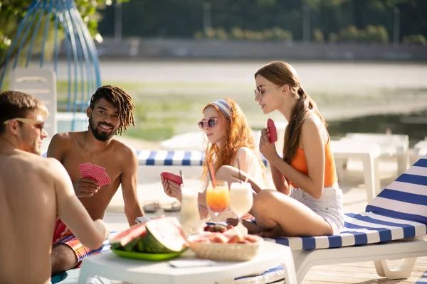 Millennials playing cards after drinking cocktails