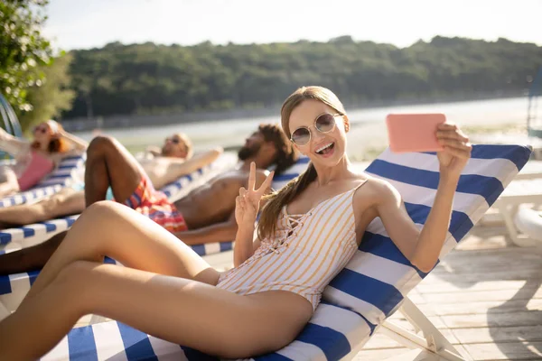 Woman wearing sunglasses smiling broadly making selfie