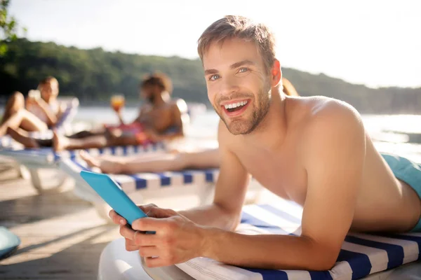 Man holding tablet while having rest near river with friends — Stock Photo, Image