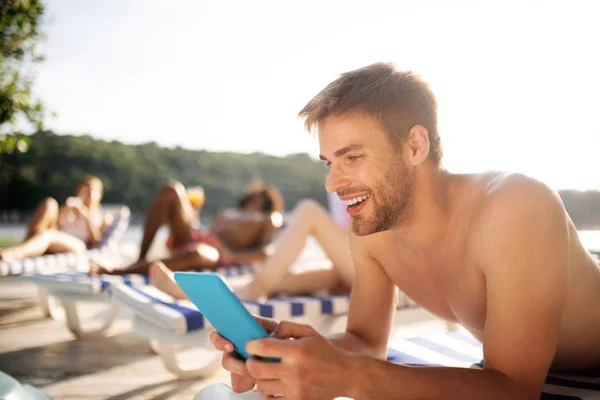 Hombre guapo de pelo oscuro sonriendo mientras ve vídeo en la tableta — Foto de Stock