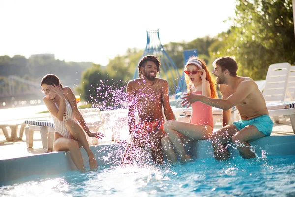 Vriendje spetteren water op vriendin terwijl je rust in de buurt van het zwembad — Stockfoto