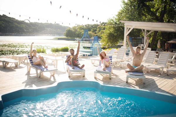 Hommes et femmes se sentent heureux et soulagés tout en se reposant près de la piscine — Photo