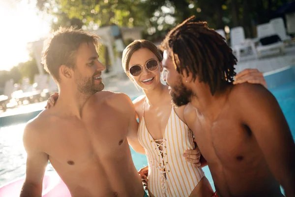 Woman wearing striped swimsuit looking at boyfriend and brother — Stock Photo, Image