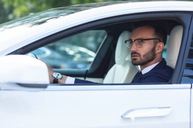 Yan aynaya bakan el saati takan sakallı adam
