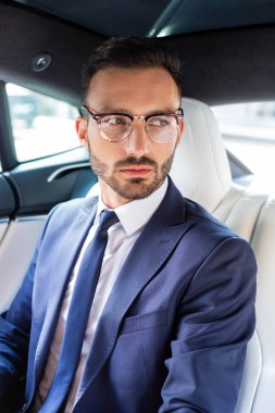 Arabada oturan koyu renk takım elbise giyen yakışıklı işadamı