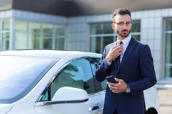 Prosperujący biznesmen noszenie okularów stojących w pobliżu jego samochodu — Zdjęcie stockowe