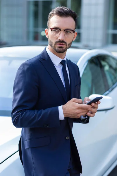 Bearded businessman texting wife while waiting for her near car — Stock Photo, Image