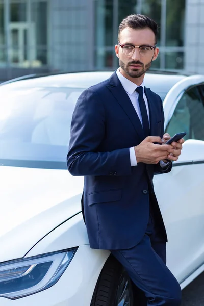 Businessman wearing suit and tie standing near car
