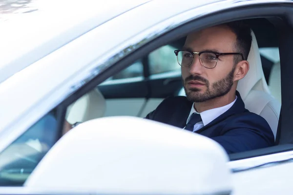 Homem de olhos escuros usando óculos carro de condução pela manhã — Fotografia de Stock