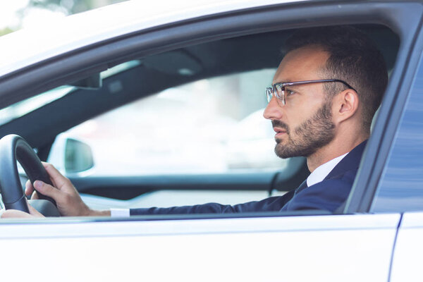 Бородатый мужчина держит руль во время вождения автомобиля
