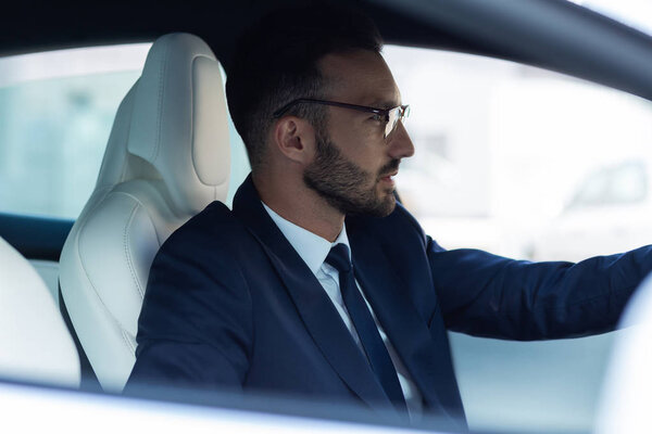Prosperous businessman feeling thoughtful while driving car