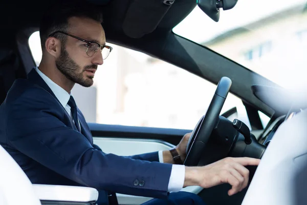 Bearded man turning music on while driving his car — Stock Photo, Image