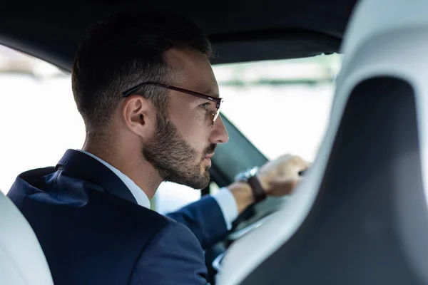 Bearded man wearing glasses looking into right side mirror — Stock Photo, Image