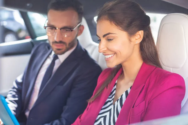 Mulher útil sorrindo enquanto sentado perto do marido no carro — Fotografia de Stock