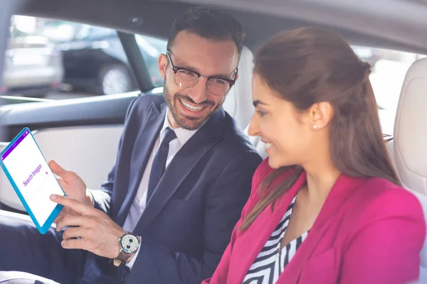 Casal sorrindo ao usar tablet sentado no carro — Fotografia de Stock