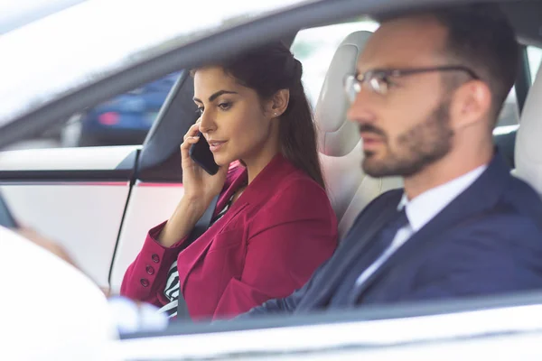 Esposa falando pelo telefone enquanto sentado perto do marido carro de condução — Fotografia de Stock