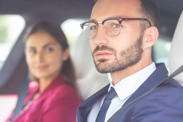 Barbudo jovem vestindo óculos sentados perto da esposa no carro — Fotografia de Stock