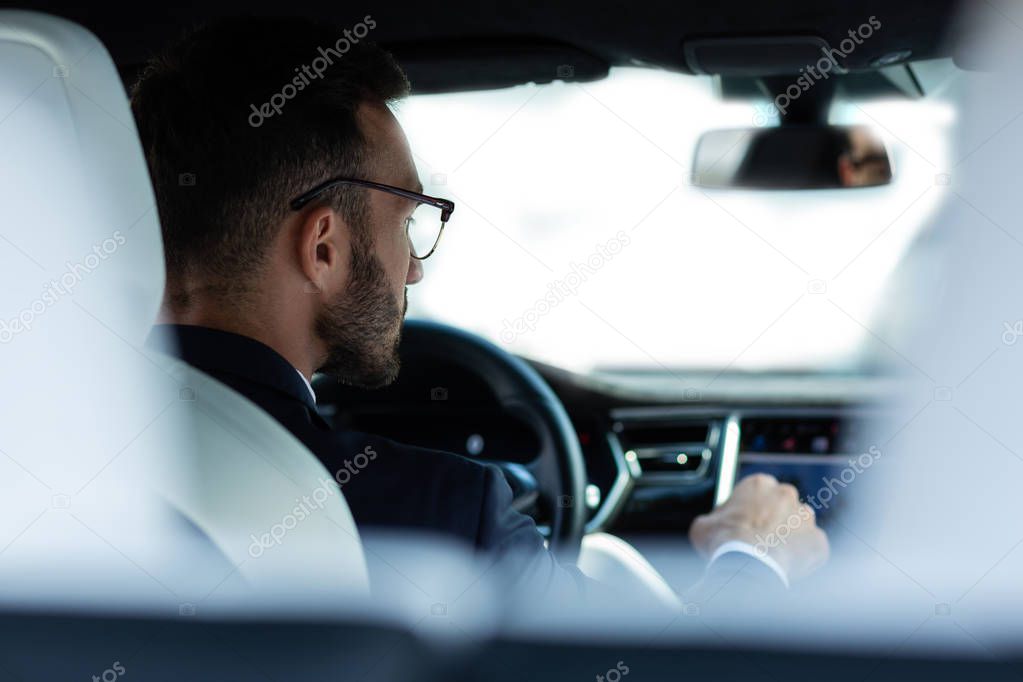 Bearded young man in glasses sitting in his car