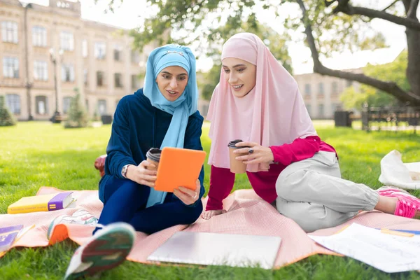 Muslimští studenti, kteří sledují video na tabletu a pití kávy — Stock fotografie