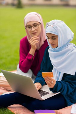 Uluslararası öğrenciler çimenlerin üzerinde otururken çevrimiçi alışveriş