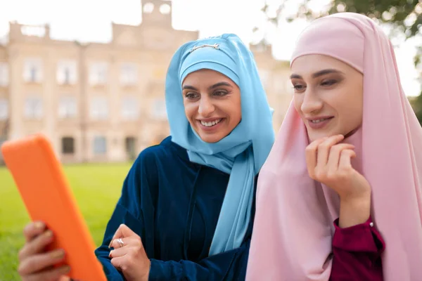 Siswa mengenakan hijab biru memegang tablet oranye duduk di dekat teman — Stok Foto